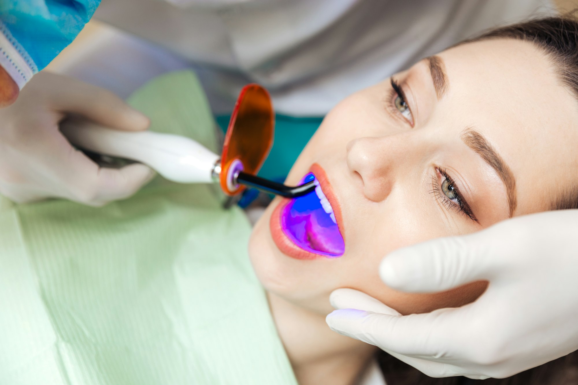 Close-up portrait of a pretty girl getting teeth bleached