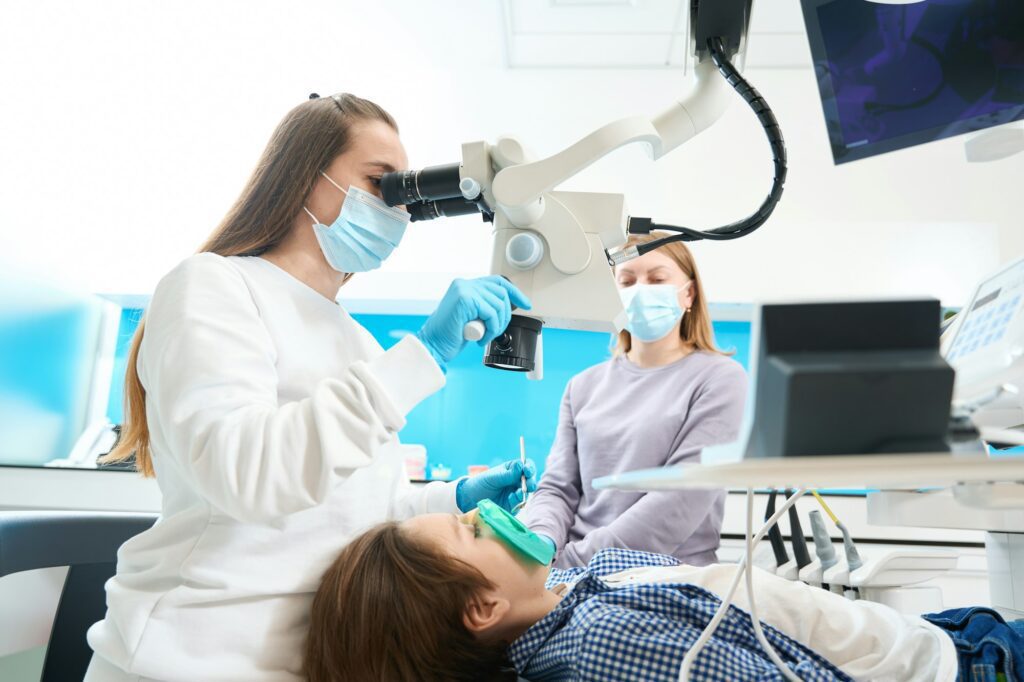 Root canal treatment for a boy in dental clinic under microscope