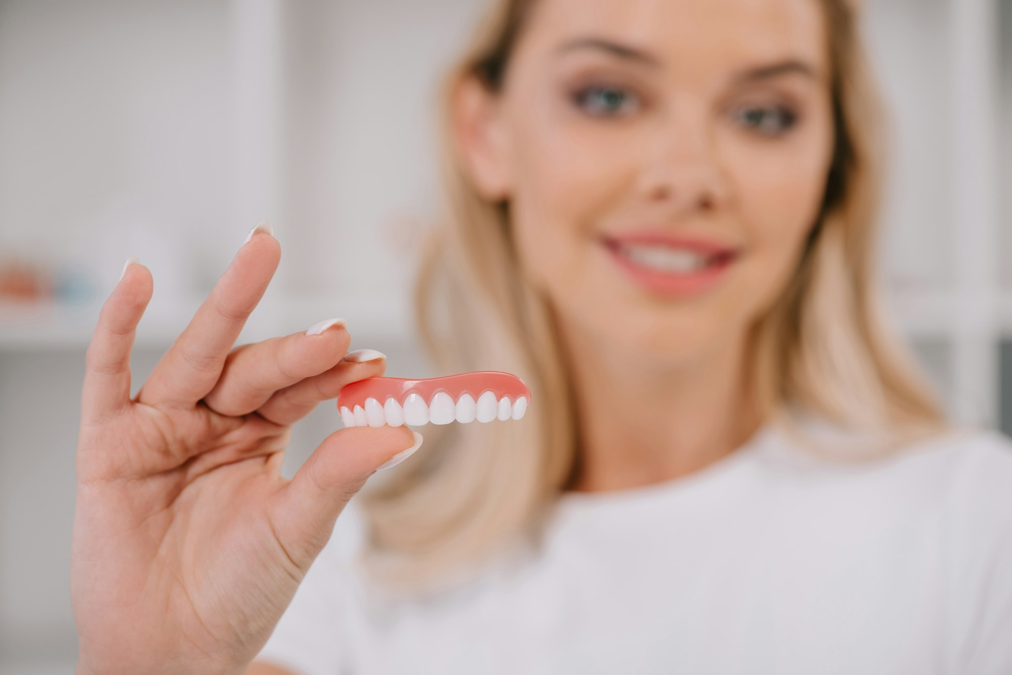 selective focus of teeth cover with smiling woman on background