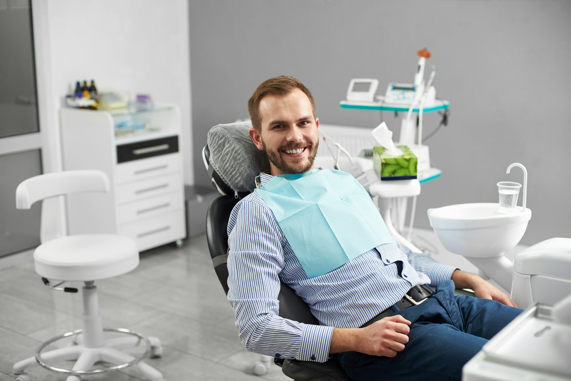 Young attractive male patient sitting in a dental chair in dentistry