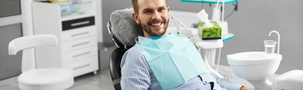 Young attractive male patient sitting in a dental chair in dentistry